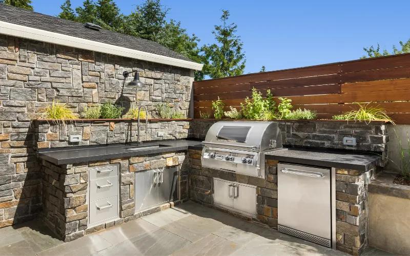 outdoor kitchen with a brand new stainless steel built-in propane grill and and cultured stone